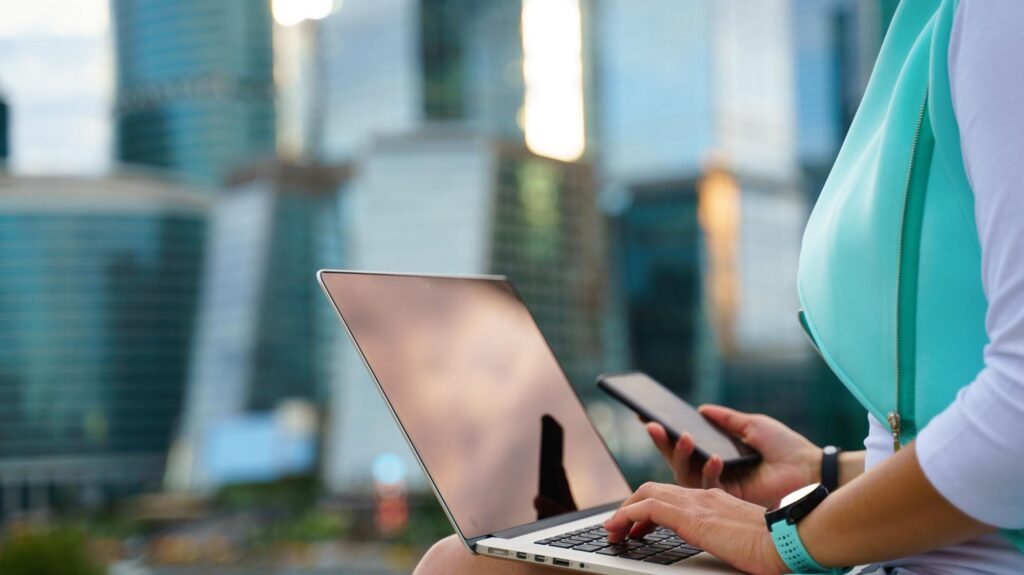 Digital marketing professional working on a laptop in a cityscape